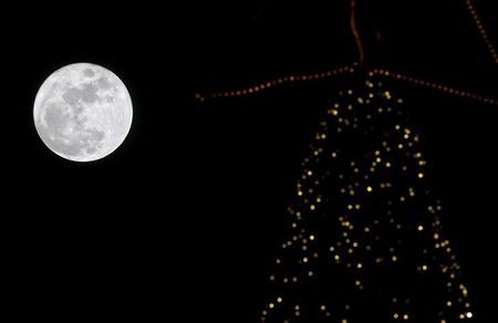 A full moon rises in the sky over a Christmas tree in Beirut Lebanon