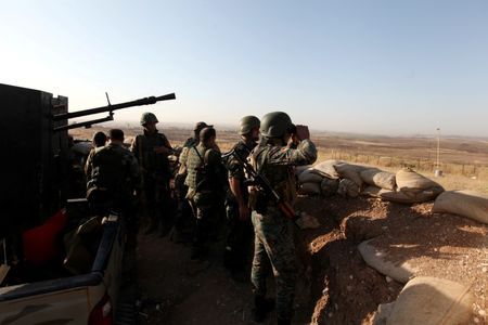 Kurdish Peshmerga forces keep watch in a village east of Mosul