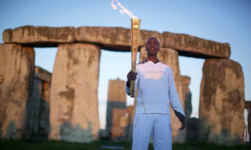 Michael Johnson with the Olympic Torch at Stonehenge in England ahead of the 2012 Games in London