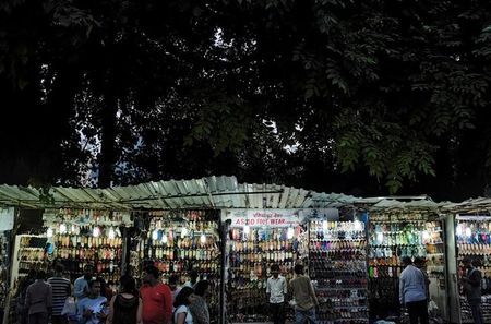 People shop for shoes at roadside shops at a market in Mumbai