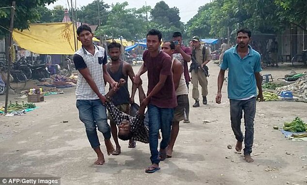 Villagers carry an injured person from the site of a militant attack at Balajan Tinali in th Kokrajhar district of northeastern Assam state