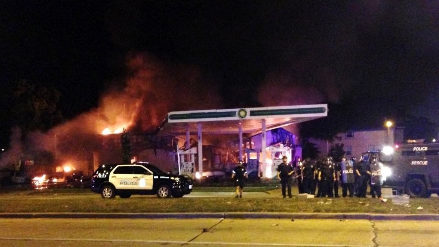 Authorities respond near a burning gas station as dozens of people protest following the fatal shooting of a man in Milwaukee Saturday Aug. 13 2016. A crowd of protesters skirmished with police Saturday night in the Milwaukee neighborhood where an offi