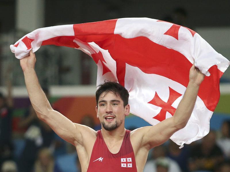 Vladimer Khinchegashvili waves the Georgian flag after winning the gold