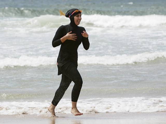 Volunteer surf life saver Mecca Laalaa runs along a beach in Sydney