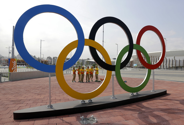 Volunteers stand near a set of Olympic Rings at Olympic Park in Rio de Janeiro Brazil Friday