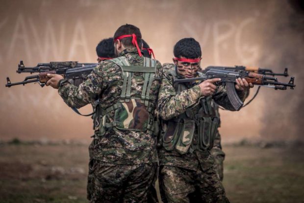 Fighters of the Kurdish People's Protection Units carry their weapons at a military training camp in Ras