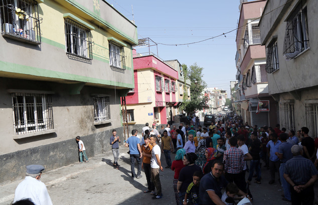 People gather near to the scene of Saturday's bomb attack targeting an outdoor wedding party that killed dozens in Gaziantep southeastern Turkey Sunday Au