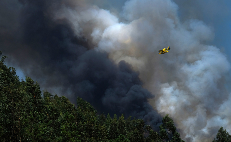 A firefighting airplane flies above a forest fire near Mortagua northern Portugal on Thursday. Firefighters in Portugal are battling multiple blazes fed by brush in a hot dry summer for a sixth straight day. A full 186 wildfires were counted Wednesday