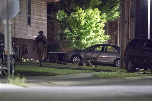 Police keep watch around a house in Strathroy Ontario Wednesday Aug. 10 2016. Canada's national police force says it has halted a possible terrorist threat but it is providing few other details