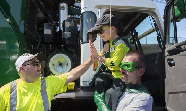 Six-year-old Ethan Dean who was diagnosed with cystic fibrosis at two weeks old gets a high five while carried by Capt. Recycle Mitch Zak during his stop at The Sacramento Bee to pick up recycling as part of his Make-A-Wish Foundation activity on Tuesd