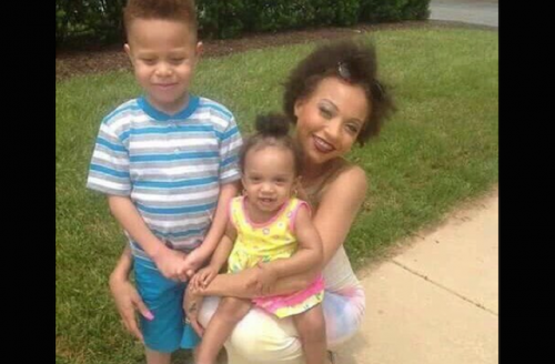 A smiling Black woman with two young children