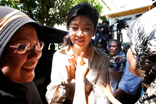 Yingluck greets her supporters during the referendum on a draft constitution outside a polling station in Bangkok. — Reuters