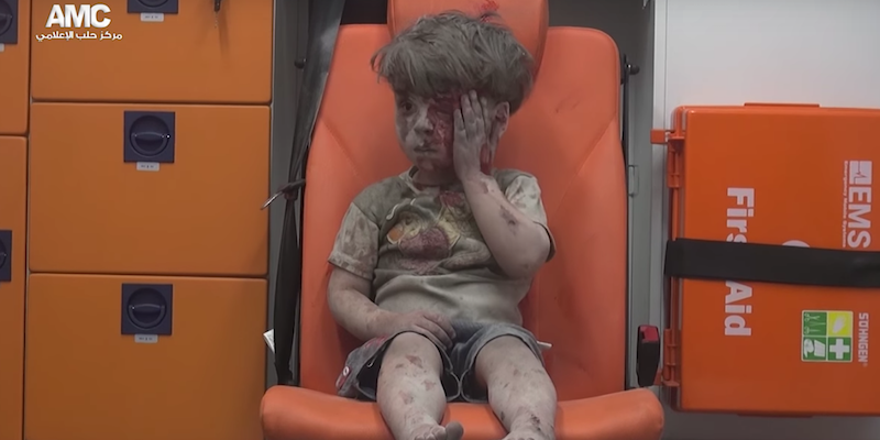 Omran Daqneesh in the back of an ambulance wiping blood off his face