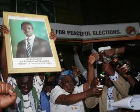 Patriotic Front general secretary Davies Chama celebrated while holding a portrait of Zambia President Edgar Chagwa Lungu after Lungu narrowly won reelection on Monday