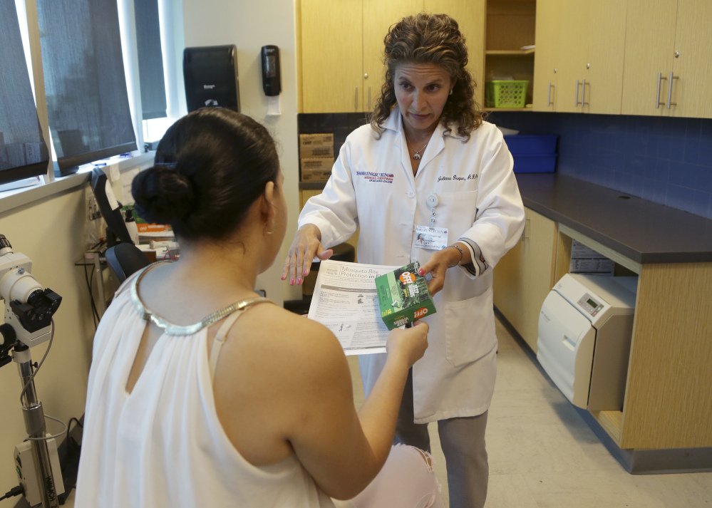 Nurse practitioner Juliana Duque right gives a patient who is in her first trimester of pregnancy insecticide and and information about mosquito protection at the Borinquen Medical Center Tuesday Aug. 2 2016 in Miami. The CDC has advised pregnant