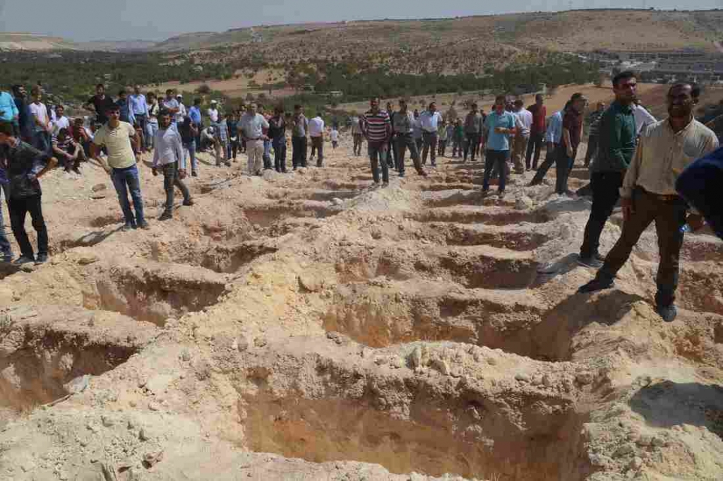 People wait close to empty graves at a cemetery on Sunday during the funeral for the victims of a suicide attack on a wedding party in Gaziantep Turkey. At least 50 people were killed when a suspected suicide bomber linked to Islamic State jihadists att