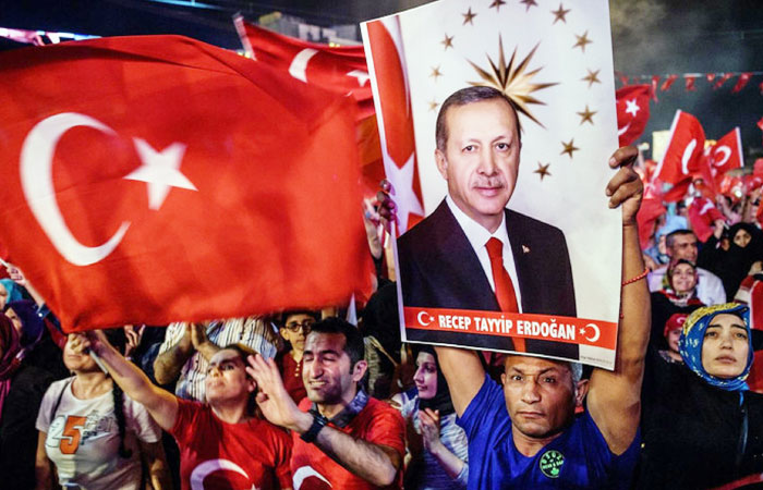 Pro-Erdogan supporters hold Turkish national flags and a portrait of Turkish President Recep Tayyip Erdogan during a rally against the military coup on Taksim square in Istanbul