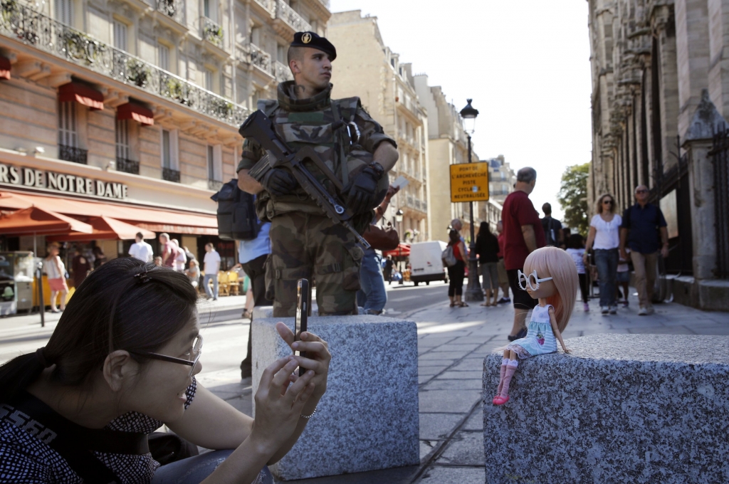 A French soldier stands guard as a tourist takes