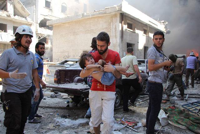 A Syrian man carries a child at the scene of a reported air strike on the rebel-held northwestern city of Idlib on Saturday