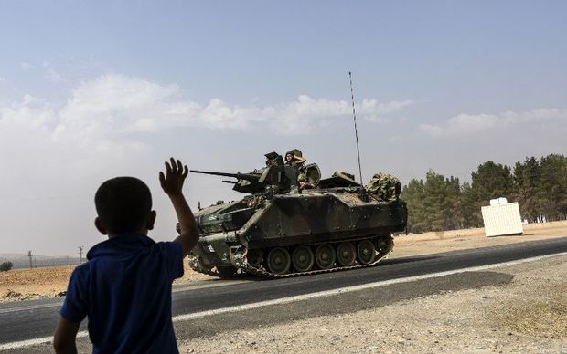 A Turkish boy waves to a Turkish tank driving into Syria from the Turkish Syrian border city of Karkamis in the southern region of Gaziantep