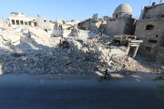 A boy rides a bicycle near rubble of damaged buildings in the rebel held al Maadi district of Aleppo