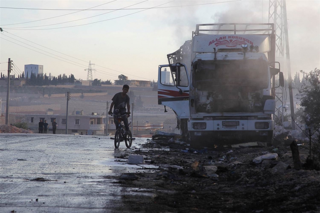 Image A boy rides a bicycle near a damaged aid truck after an airstrike on the rebel held Urm al Kubra town