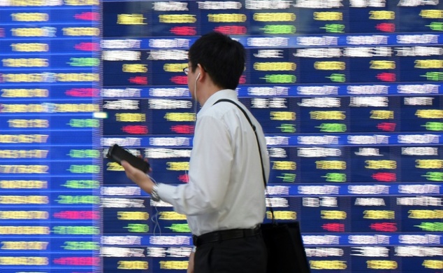 A businessman walks past an electric quotation board displaying the Nikkei key index of the Tokyo Stock Exchange in Tokyo