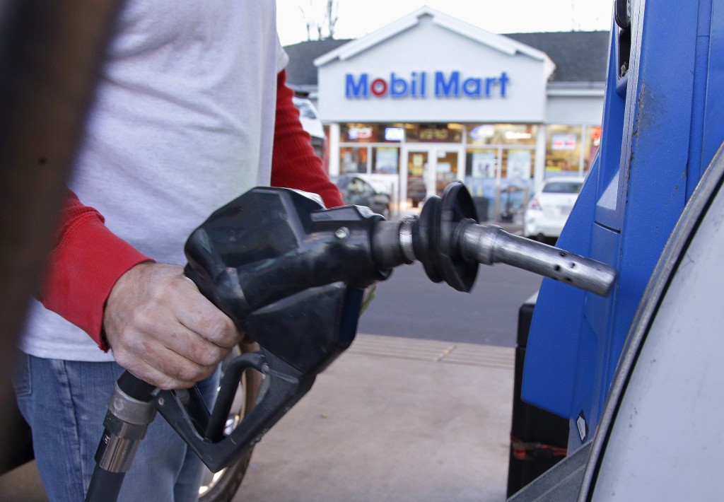 A customers prepares to pump gas on Monday Dec. 7 2015 at a gas station in Pembroke Mass. The price of a barrel of oil fell Monday to a nearly seven-year low. With OPEC's decision to keep pumping at current levels analysts expect oil to remain relati