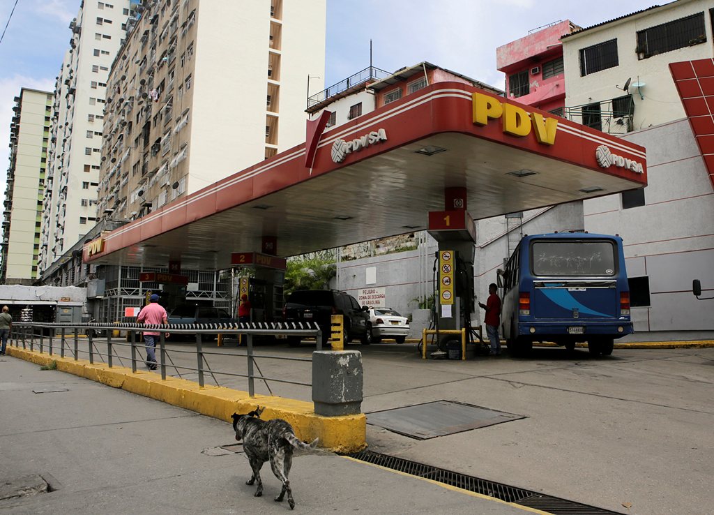 A dog walks past a gas station with the logo of the Venezuelan state oil company PDVSA in Caracas Venezuela