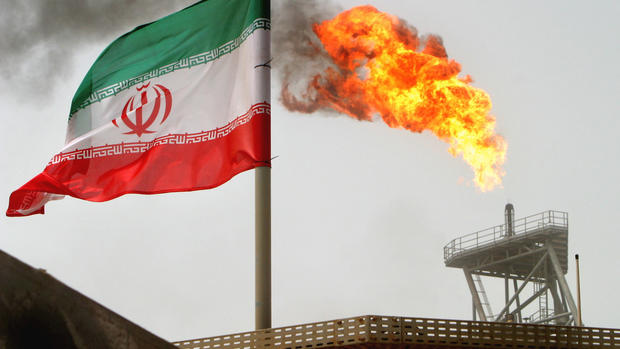 A gas flare on an oil production platform is seen alongside an Iranian flag in the Gulf