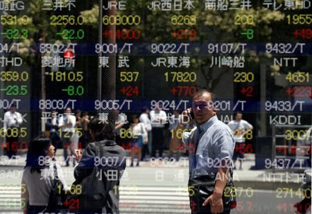 A man is reflected in a stock quotation board outside a brokerage in Tokyo