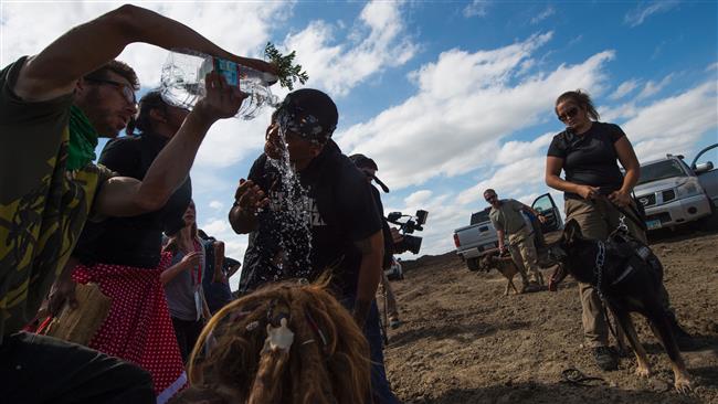 A man pours water over the eyes of a protester after he was pepper-sprayed by security contractors