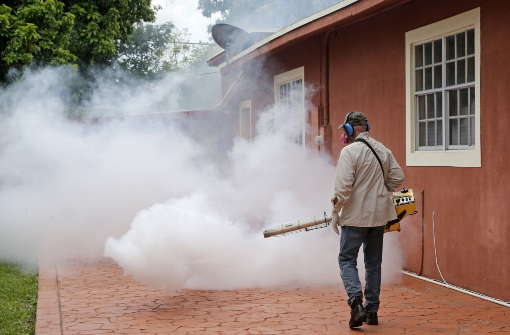 A Miami Dade County mosquito control worker sprays around a home in the Wynwood area of Miami on Monday Aug. 1 2016. The CDC has issued a new advisory that says pregnant women should not travel a Zika-stricken part of Miami and pregnant women who live