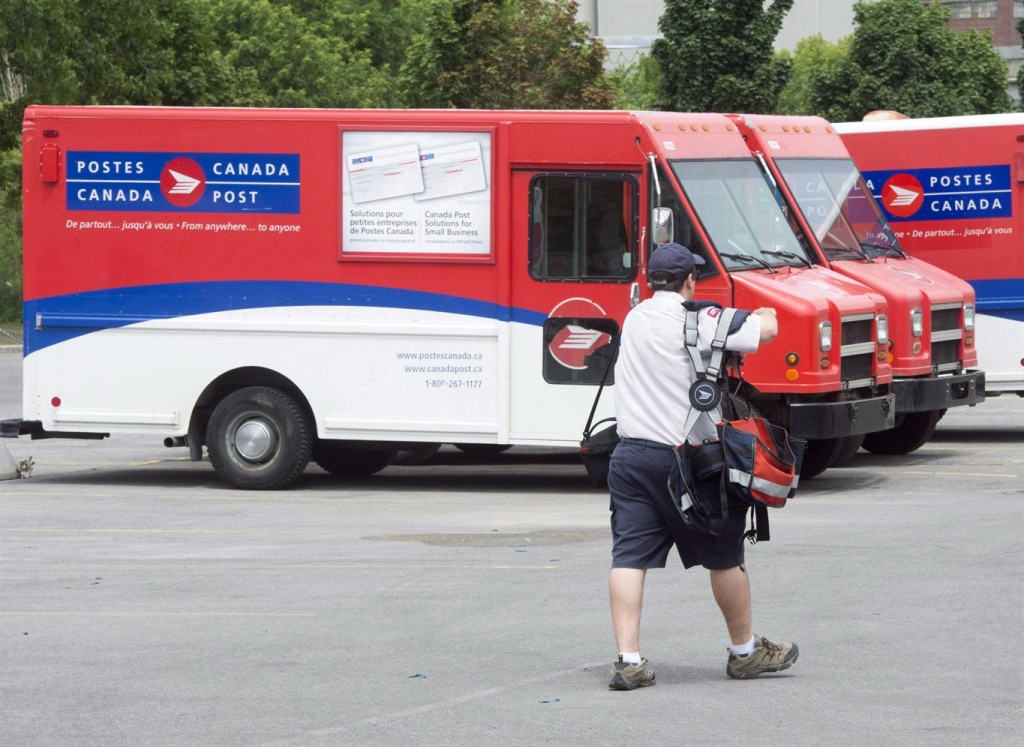 A postal worker walks past Canada Post trucks at a sorting centre in Montreal