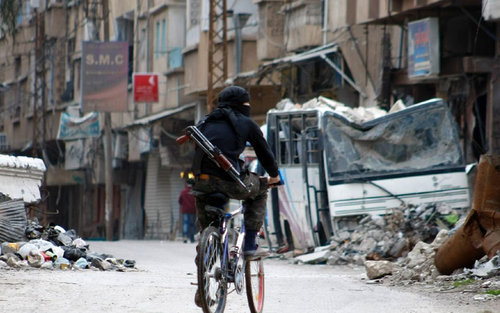 A rebel fighter carrying a weapon rides his bike in 2014 in a street in the northeastern city of Deir Ezzor