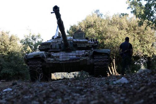 A rebel fighter walks next to a tank in Jubata al-Khashab in Quneitra countryside Syria