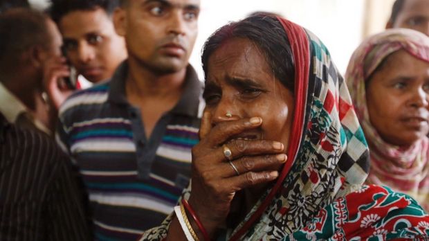 A relative of a fire victim cries as victims bodies are carried into a makeshift morgue