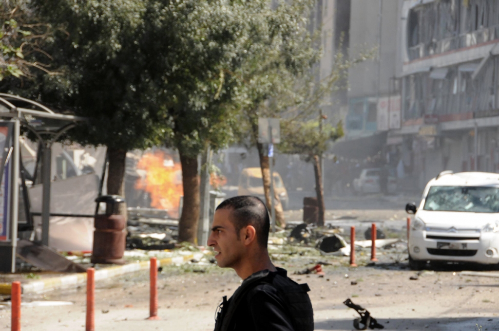 A security member guarding the site of a car bomb attack in the city center of Van eastern Turkey Monday Sept. 12 2016