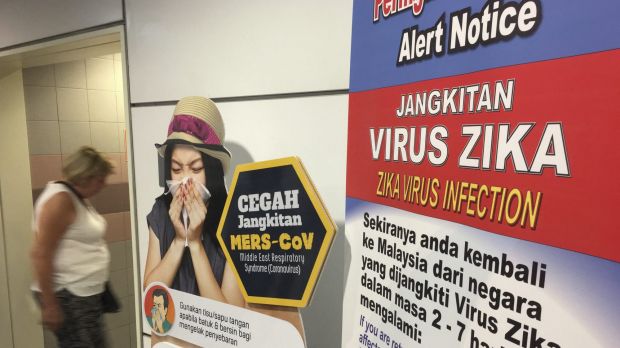 A traveller walks past a travel advisory on the Zika virus infection in Kuala Lumpur International Airport