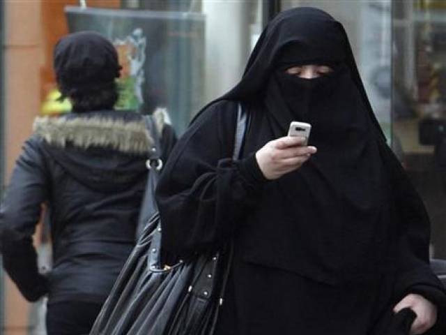 A woman wears a burqa as she walks on a street in Saint-Denis near Paris