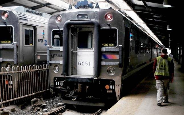 A worker walks past idle New Jersey Transit commuter trains in the Hoboken station in Hoboken