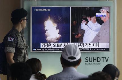 A man watches a TV screen showing a file image of Kim Yong Jin second from left a vice premier on education affairs in North Korea's cabinet and North Korean leader Kim Jong Un second from right at the Seoul Railway Station in Seoul South Korea