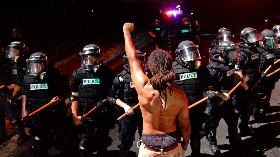 A protester stands with his fist clenched in front of a line of police officers in Charlotte North Carolina on Sept. 20