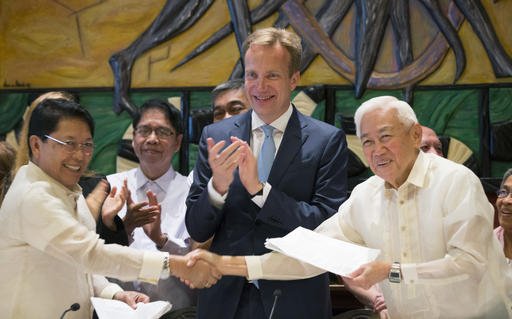 Jesus Dureza left representative of the Philippine government and Luis Jalandoni representative of the communist movement National Democratic Front of the Philippines right shake hands as Norwegian Foreign Mi