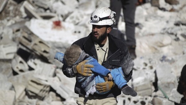 A civil defence member carries a dead child in a site hit by airstrikes in the rebel-controlled area of Maaret al Numan town in Idlib province Syria