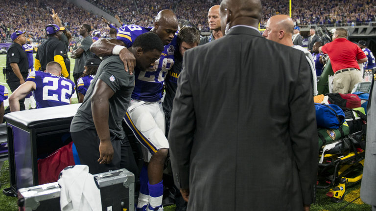 Adrian Peterson is helped to the locker room after injuring his knee on Sunday