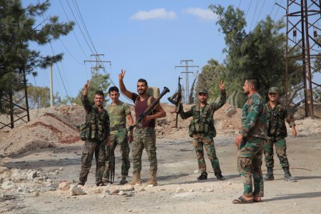 Forces loyal to Syria's President Bashar al Assad flash victory signs as they stand at a military complex after they recaptured areas in southwestern Aleppo on Sunday that rebels had seized last month Syria in this handout