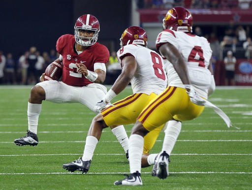 Alabama quarterback Jalen Hurts left carries as Southern California defensive back Iman Marshall and defensive back Chris Hawkins defend during the first half of an NCAA college football game Saturday Sept. 3 2016 in Arlington Texas. (AP Pho