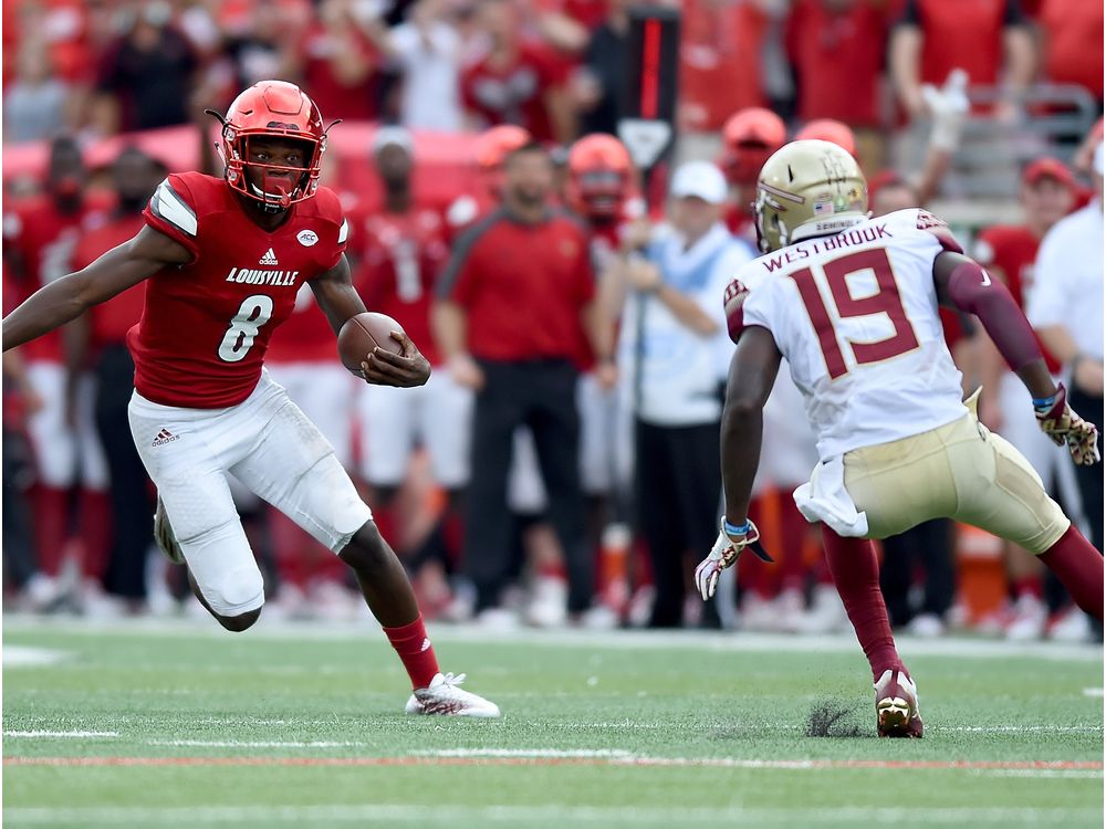 Lamar Jackson left of the Louisville Cardinals runs past A.J. Westerbrook of the Florida State Seminoles duriing the fourth quarter of the game at Papa John's Cardinal Stadium