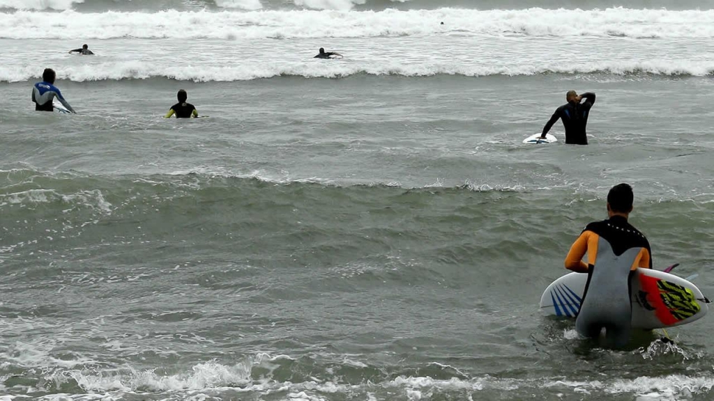 Surfers make their way toward waves Tuesday Sept. 6 2016 along the coast of South Kingstown R.I. as Tropical Storm Hermine begins to weaken